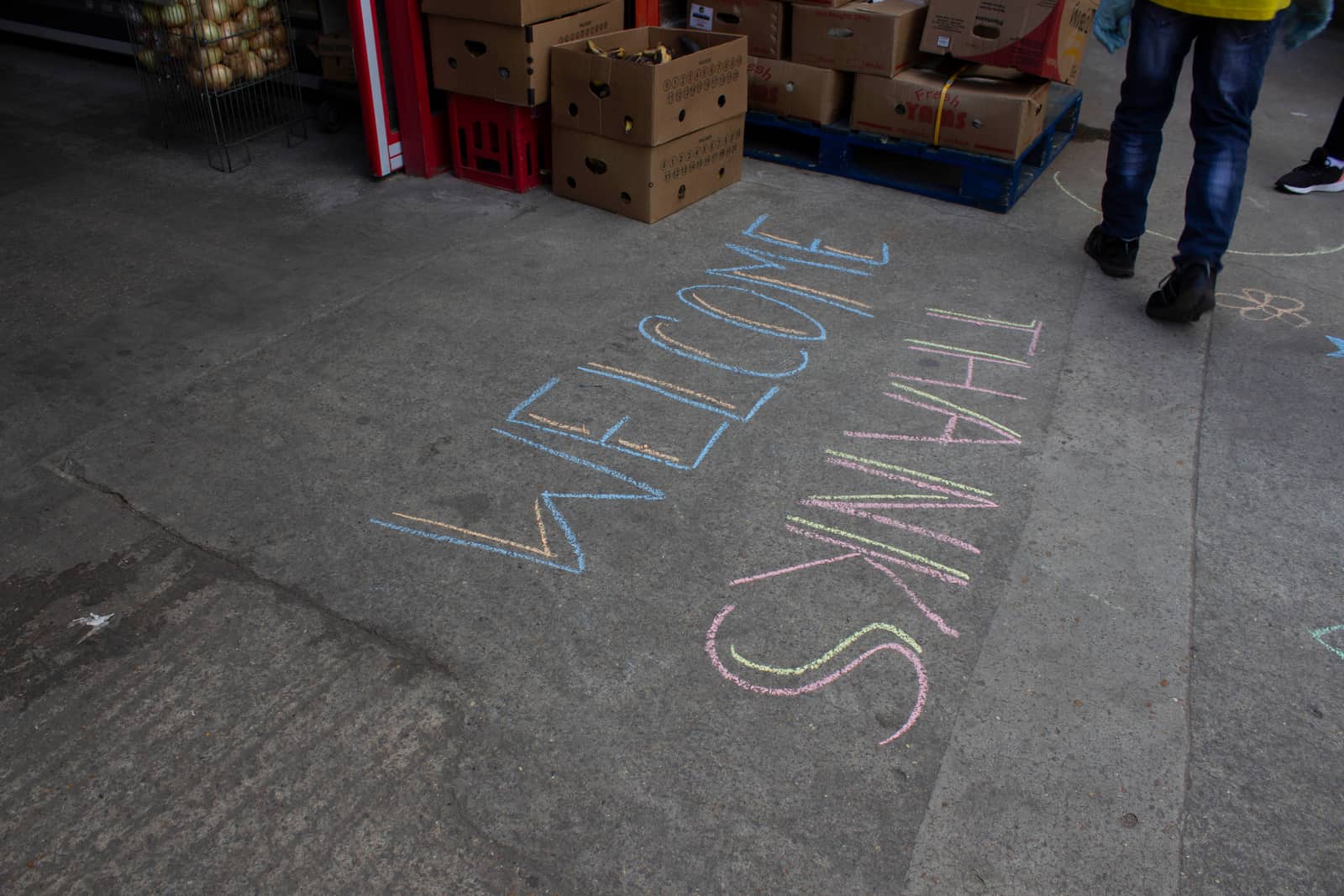 The words WELCOME and THANKS written in chalk on a warehouse floor