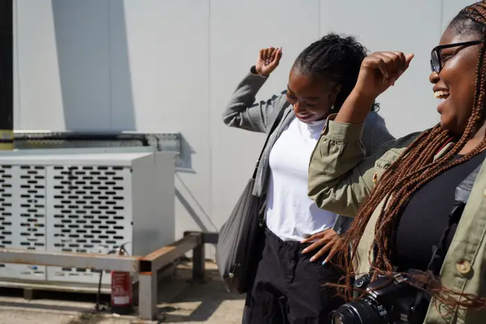 Two young women laughing and dancing outside