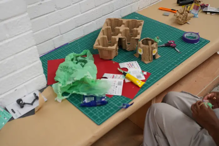 Cardboard models mid-build on a green cutting mat