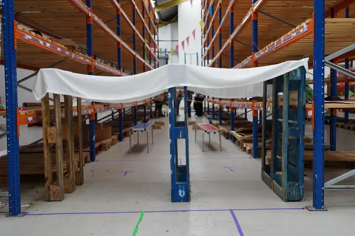 A white canopy strung between warehouse racking over benches
