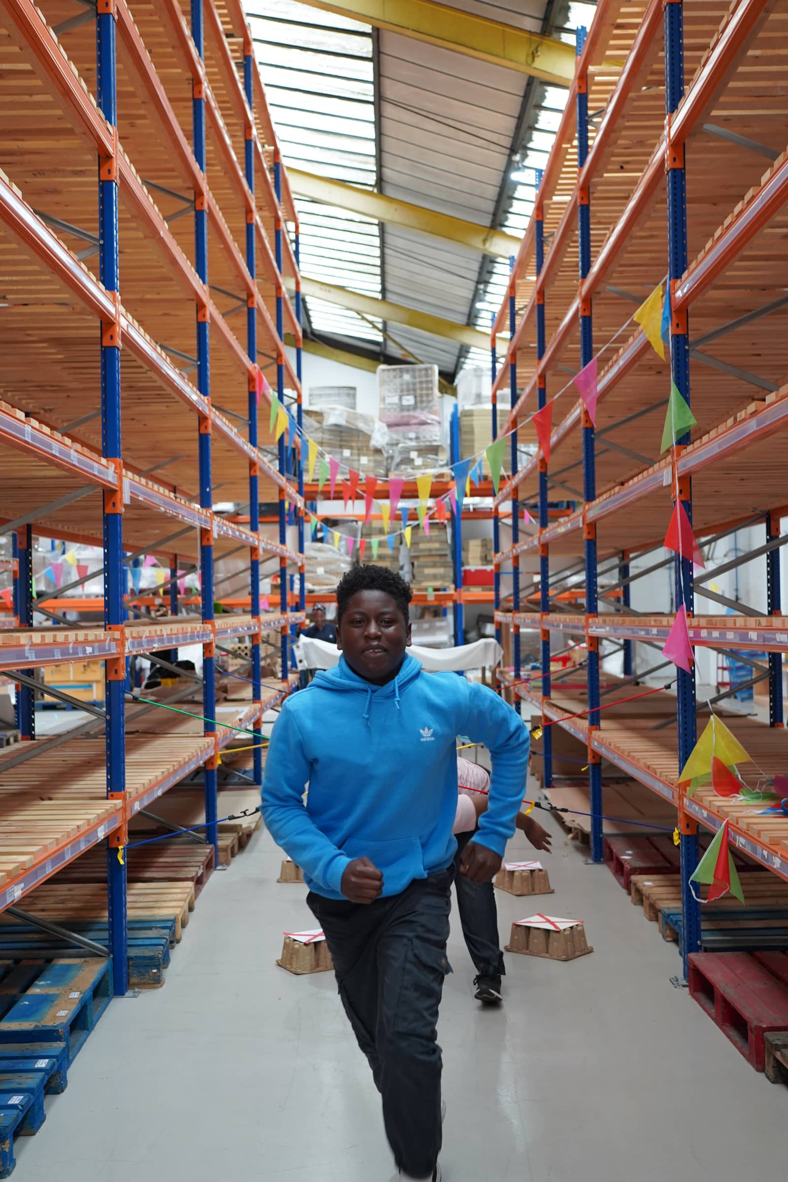 A young person running down a warehouse aisle strung with paper flags